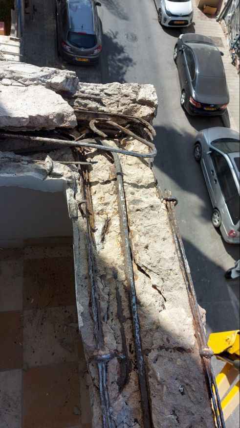ברזל חלוד ובטון מתפורר במעקה מרפסת לפני שיקום