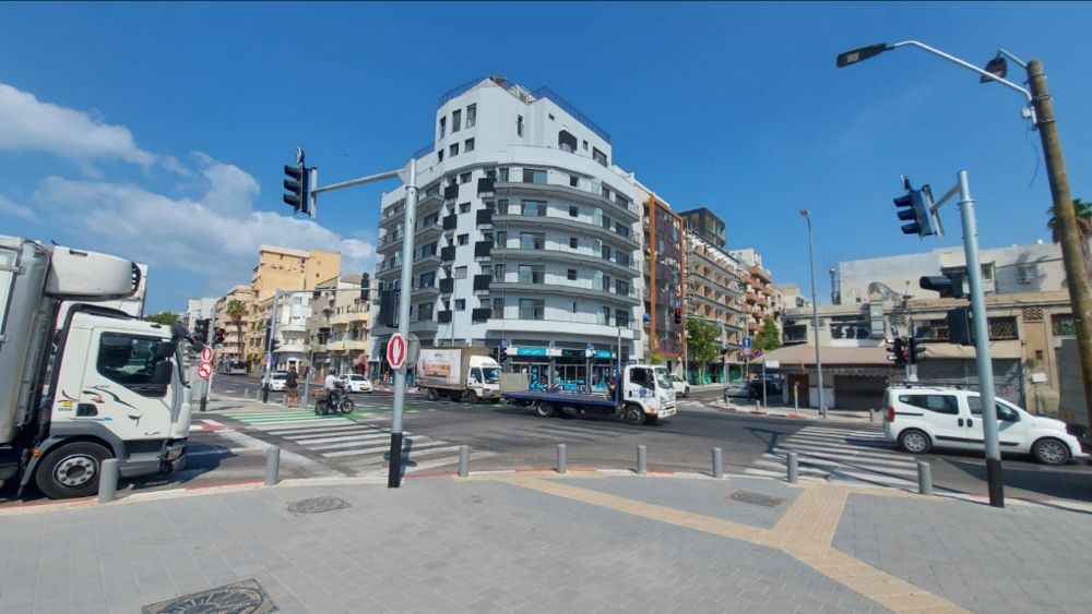 בניין לבן בפינת רחוב אחרי צביעת החזית בשני צבעים
